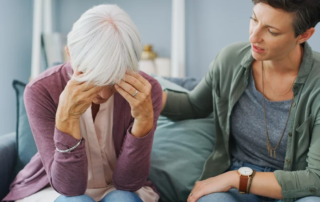 Senior woman struggles with mental health alongside a younger caregiver.