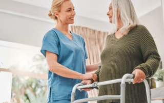 Care associate helping a senior with her walker in an assisted living community.