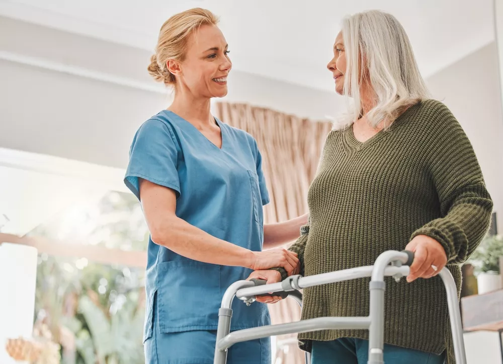 Care associate helping a senior with her walker in an assisted living community.